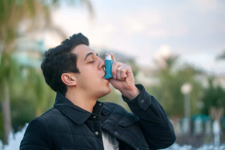 man using asthma inhaler