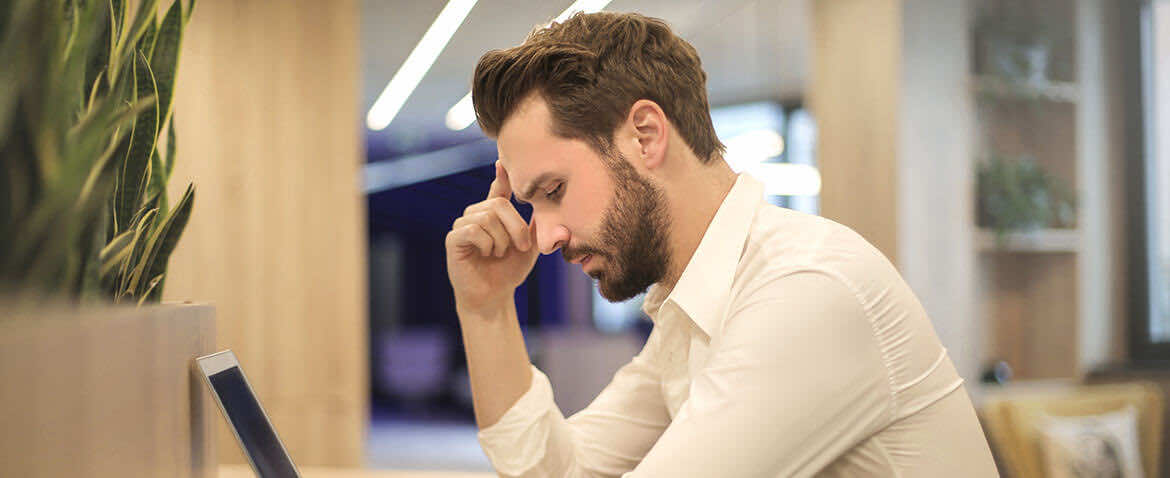 man at office desk looking down | onsite GP service | London Doctors Clinic