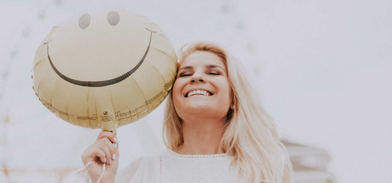 Woman smiling with a balloon | Women's Health | London Doctors Clinic